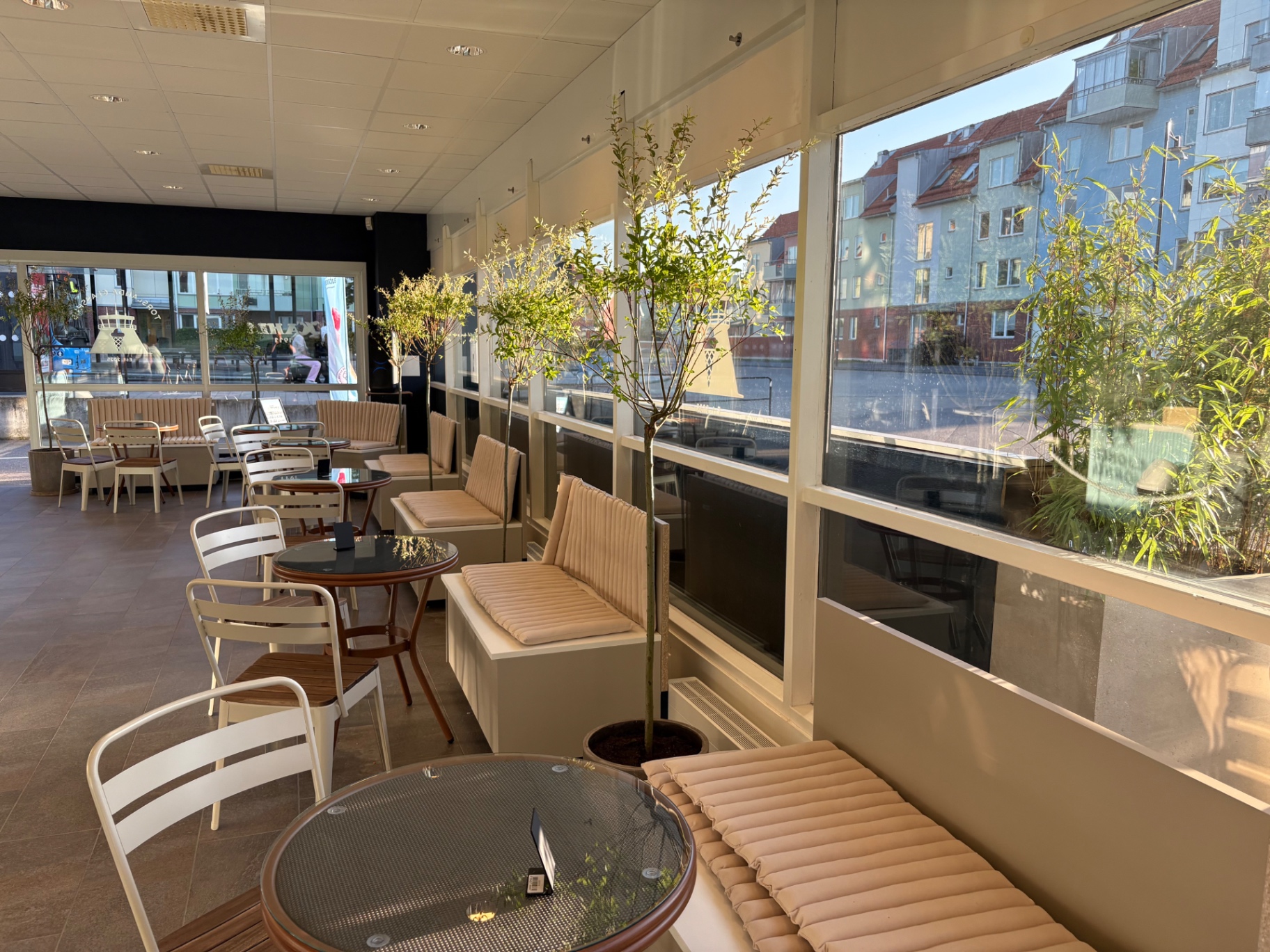 Ljus inredning med bord och stora fönster inne i glasshuset